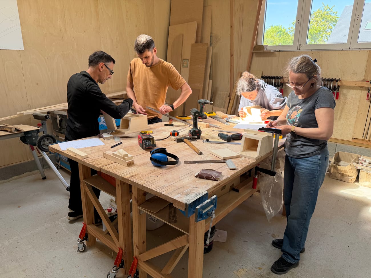 Quatre participants à l’établi pendant un team building bois