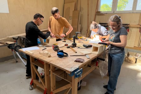 Quatre participants à l’établi pendant un team building bois